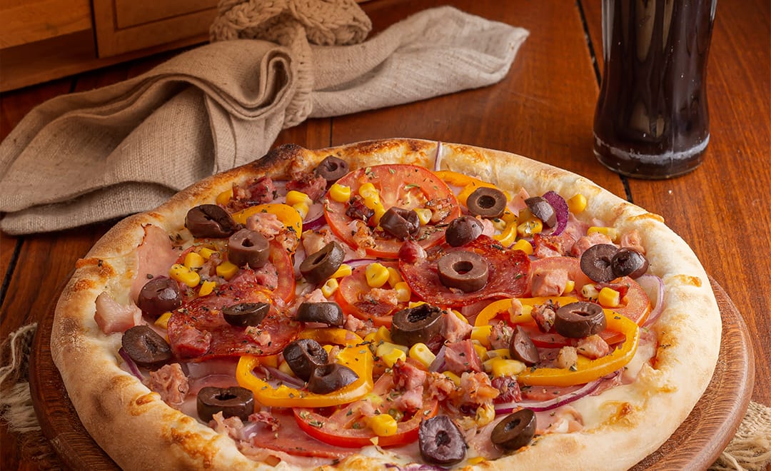 Pizza de calabresa, milho, azeitona e pimentão na mesa